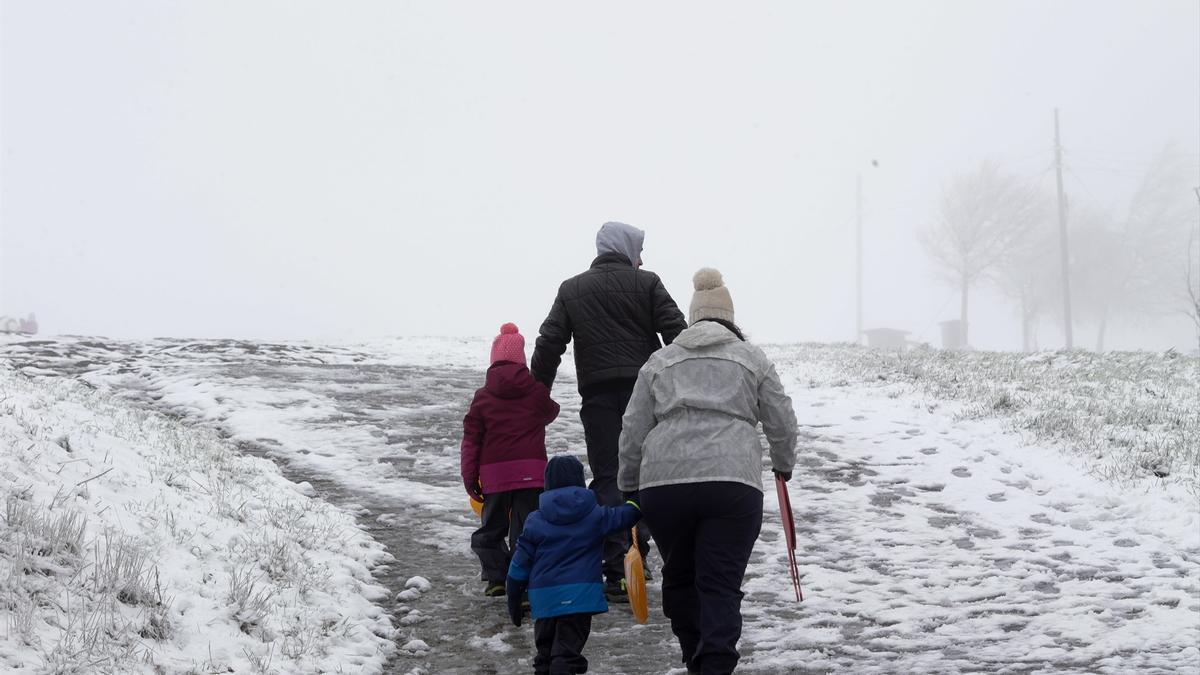 Una familia pasea en un paisaje nevado.