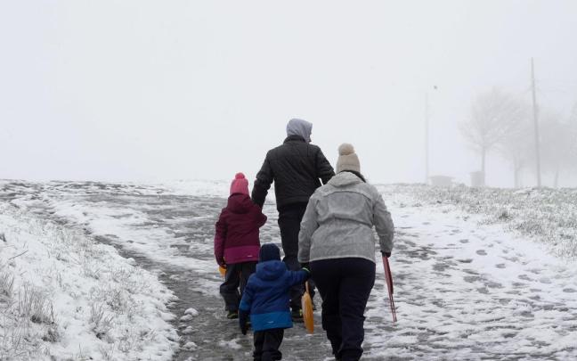 Una familia pasea en un paisaje nevado.