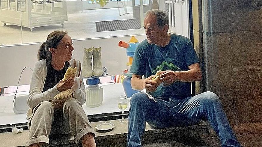 Un hombre y una mujer aprovechan un escaparate para reponer fuerzas.