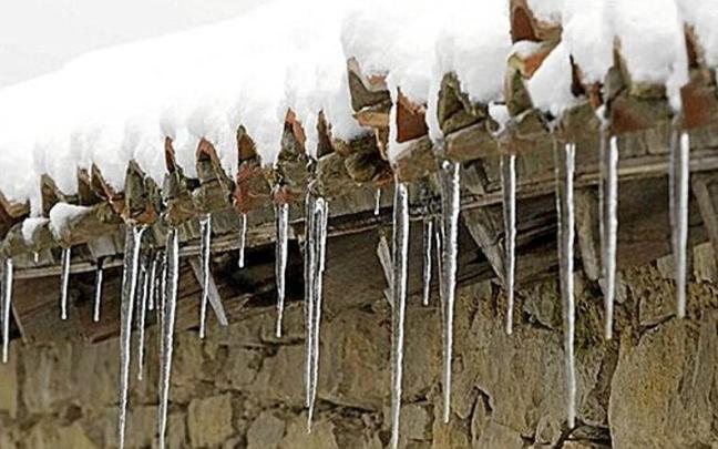 Carámbanos de hielo cuelgan del alero de una casa con un tejado cargado de nieve como consecuencia de un temporal pasado que azotó al territorio. Carámbanos de hielo cuelgan del alero de una casa con un tejado cargado de nieve como consecuencia de un temporal pasado que azotó al territorio.
