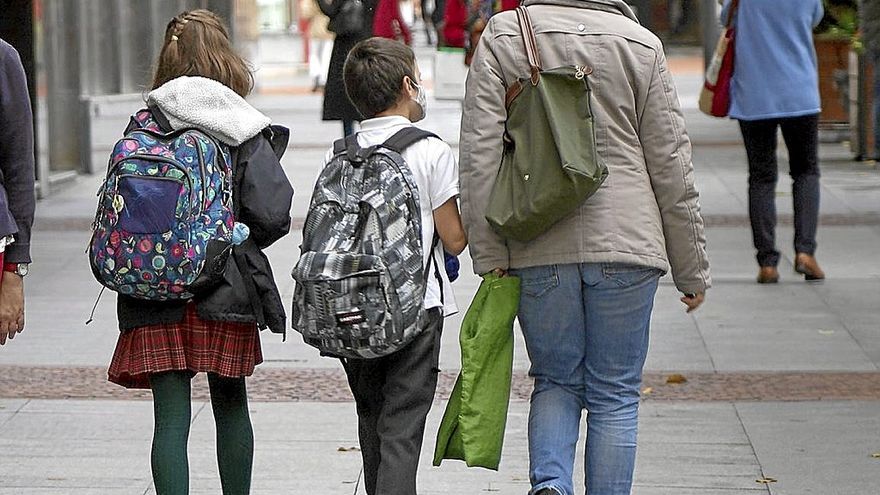 Dos menores caminan con sus mochilas por Bilbao en compañía de una mujer. | FOTO: PABLO VIÑAS