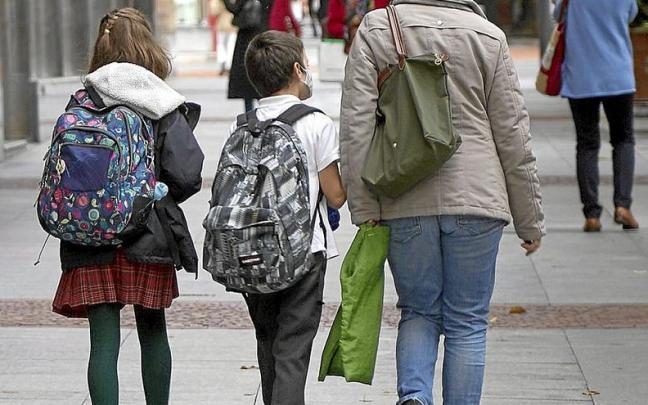 Dos menores caminan con sus mochilas por Bilbao en compañía de una mujer. | FOTO: PABLO VIÑAS Dos menores caminan con sus mochilas por Bilbao en compañía de una mujer. | FOTO: PABLO VIÑAS