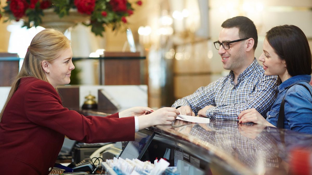 Una pareja hace el check-in en la recepción de un hotel.