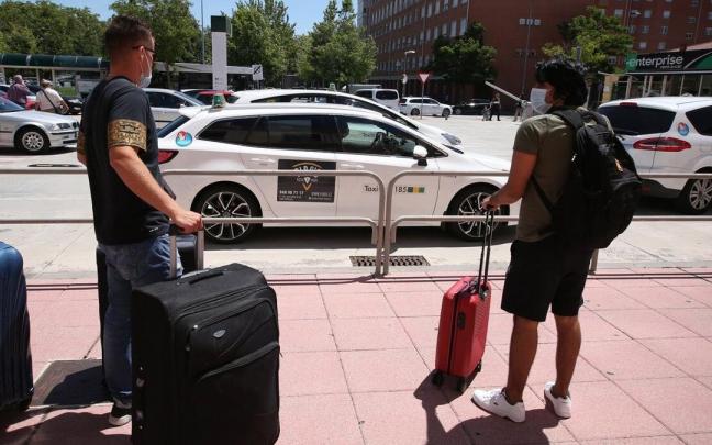 Personas junto a la parada de taxis de la estación de tren.