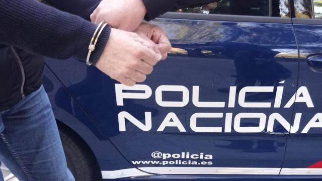 Un hombre esposado y conducido por un agente Un hombre esposado y conducido por un agente