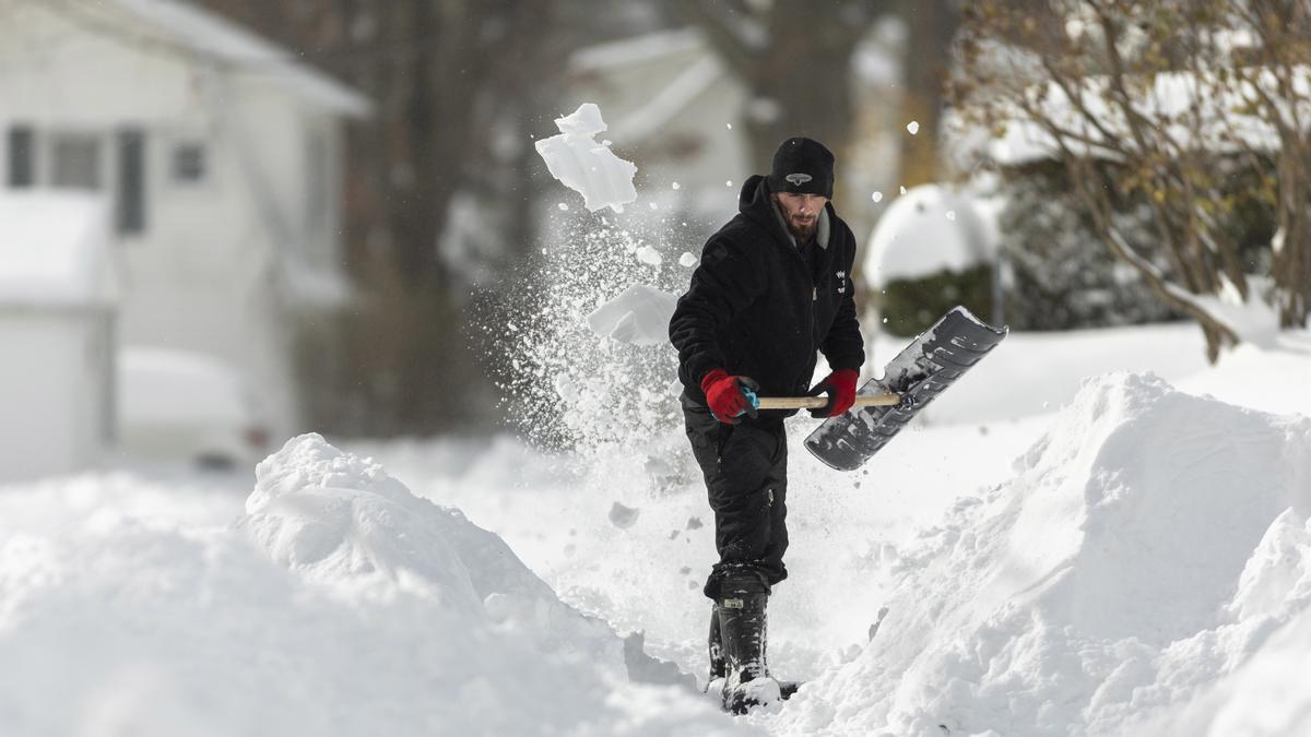 Un ciudadano retira la nieve caida en una vía pública.