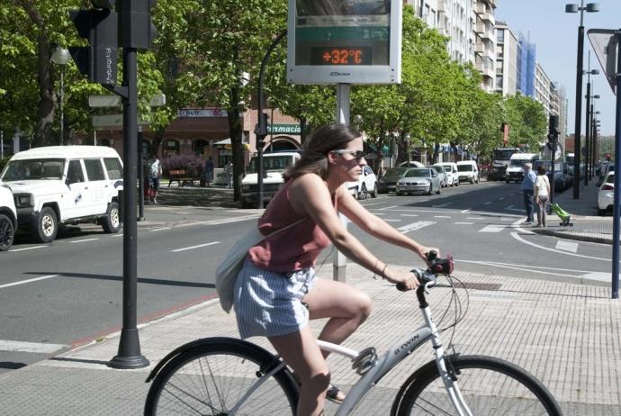 Una joven circula en bicicleta delante de un termómetro en la Avenida Gasteiz