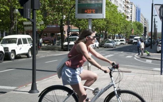 Una joven circula en bicicleta delante de un termómetro en la Avenida Gasteiz