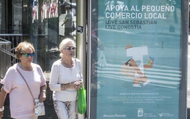 Dos mujeres pasan junto a un anuncio del comercio local. Dos mujeres pasan junto a un anuncio del comercio local.