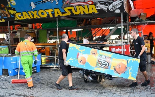 Dos hombres trabajan en el desmontaje de una txosna en El Arenal mientras un operario limpia las inmediaciones