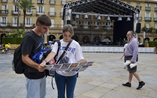 Unos j&oacute;venes turistas escudri&ntilde;an un plano de Bilbao en la Plaza Nueva