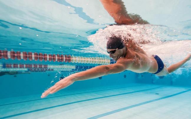 Un hombre nada en una piscina olímpica. Un hombre nada en una piscina olímpica.