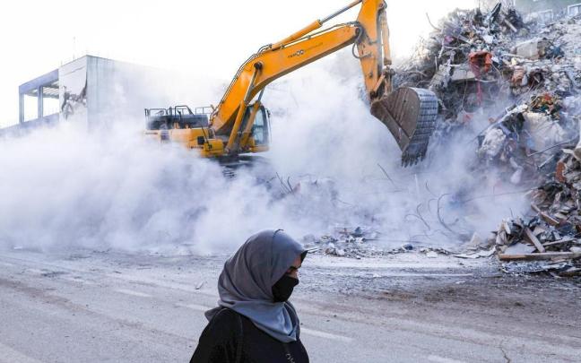 Una mujer pasea ante un edificio derrumbado por el terremoto.