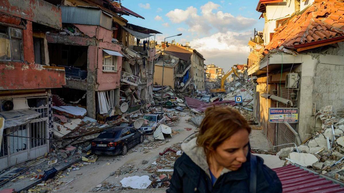 Una mujer, ante una calle repleta de edificios colapsados en Hatay.