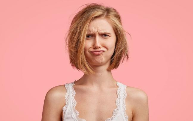 Una mujer con el pelo encrespado y con cara de disgusto. Una mujer con el pelo encrespado y con cara de disgusto.