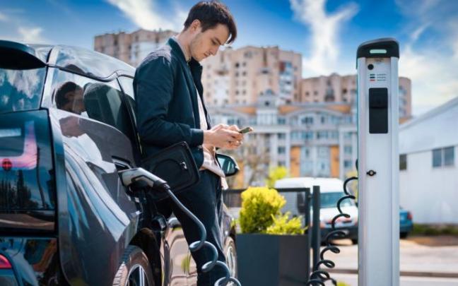 Un hombre recarga su coche eléctrico. Un hombre recarga su coche eléctrico.