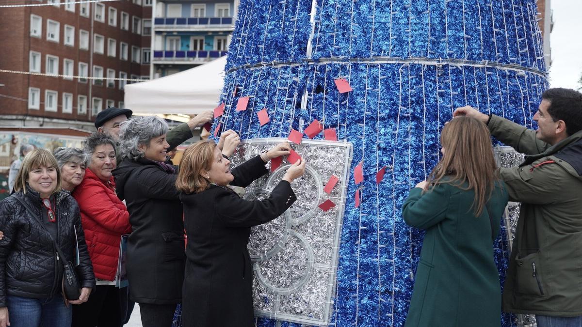 Los participantes ayer en el primer cuelgue de deseos en el árbol sito en Deusto