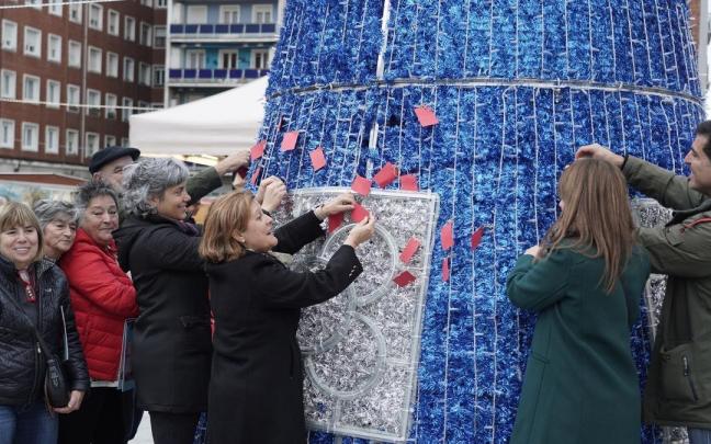 Los participantes ayer en el primer cuelgue de deseos en el árbol sito en Deusto