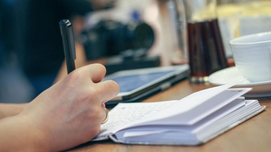 Imagen de una persona escribiendo en un cuaderno.