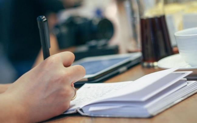 Imagen de una persona escribiendo en un cuaderno. Imagen de una persona escribiendo en un cuaderno.