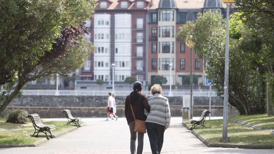 Una mujer acompaña a una persona mayor durante un paseo.