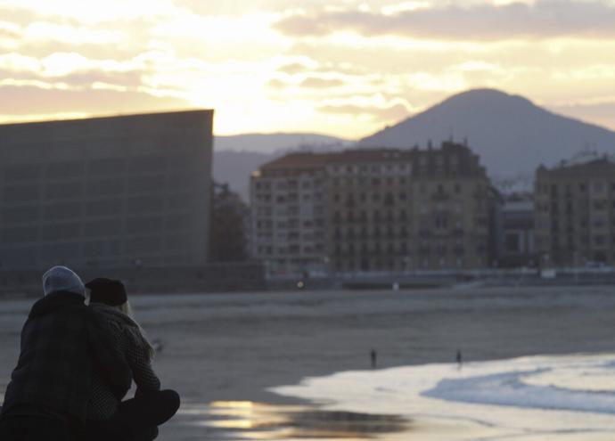 Dos personas ven el atardecer desde el muro de Sagües en Donostia