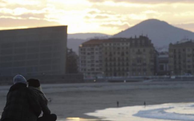 Dos personas ven el atardecer desde el muro de Sagües en Donostia