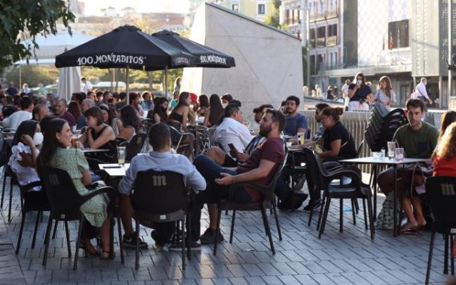 Varias personas con mascarillas sentadas en una terraza