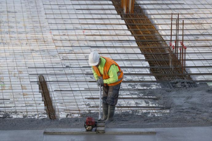 Un trabajador alisa el hormigón en la construcción de un edificio de viviendas