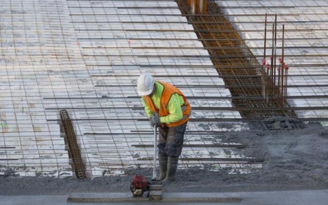 Un trabajador alisa el hormigón en la construcción de un edificio de viviendas Un trabajador alisa el hormigón en la construcción de un edificio de viviendas
