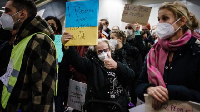 Una mujer sostiene un cartel que dice "ofrezco habitación para una madre y un niño", en la estación central de Berlín.