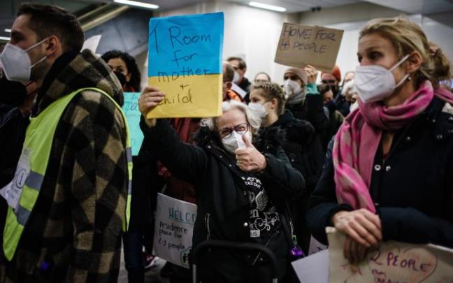 Una mujer sostiene un cartel que dice "ofrezco habitación para una madre y un niño", en la estación central de Berlín. Una mujer sostiene un cartel que dice "ofrezco habitación para una madre y un niño", en la estación central de Berlín.