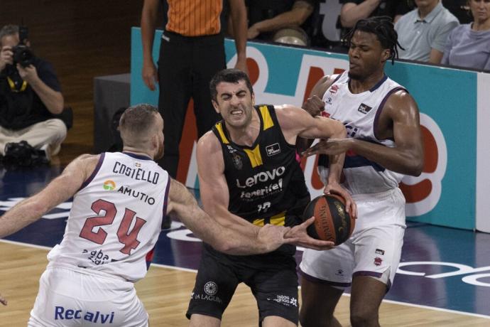 El pívot del Lenovo Tenerife Giorgi Shermadini (c) lucha con Steven Enoch (d) y con Matt Costello, ambos del Baskonia