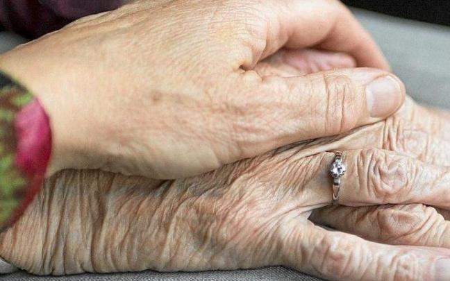 Emakume batek pertsona heldu baten eskua laztantzen du.