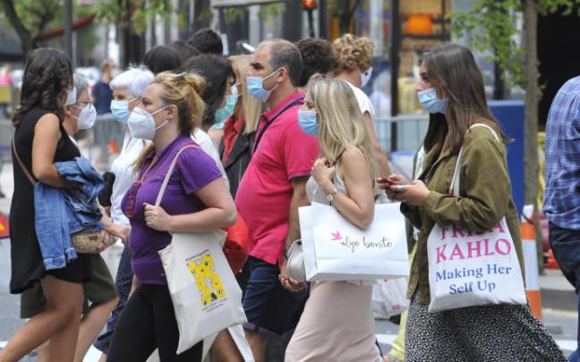 Un grupo de personas pasea por la calle con mascarilla. Un grupo de personas pasea por la calle con mascarilla.