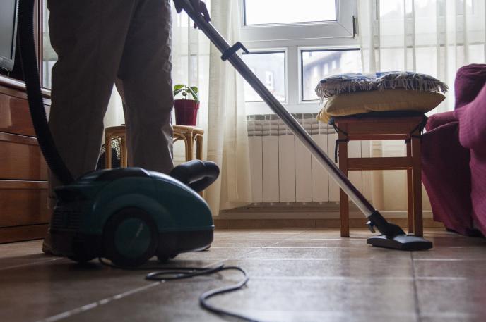 Mujer pasando el aspirador a una habitación.