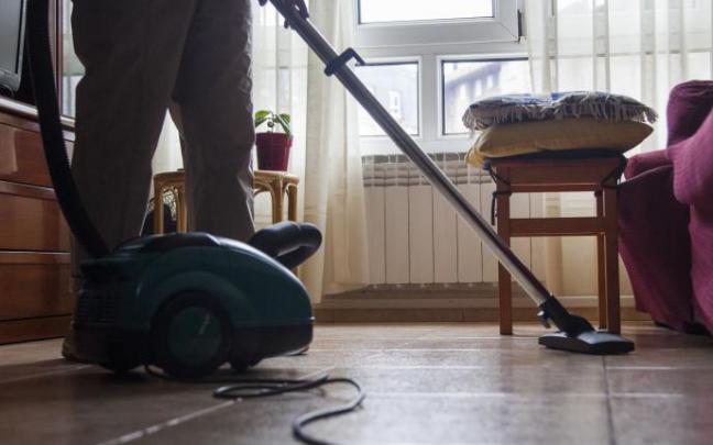 Mujer pasando el aspirador a una habitación