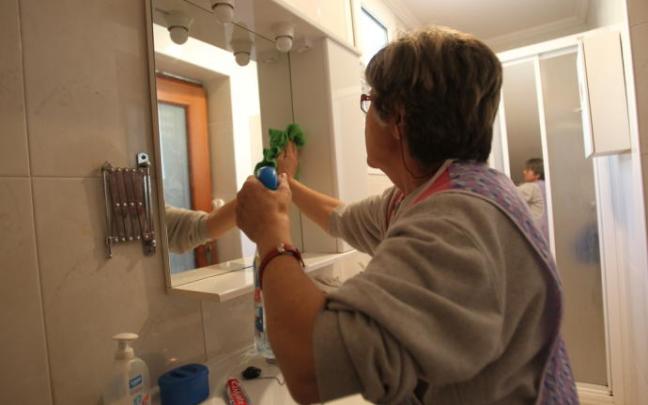 Una mujer limpiando el espejo de un baño. Una mujer limpiando el espejo de un baño.