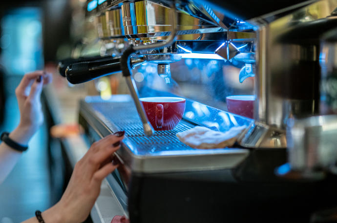 Una empleada en una cafetería prepara un café.