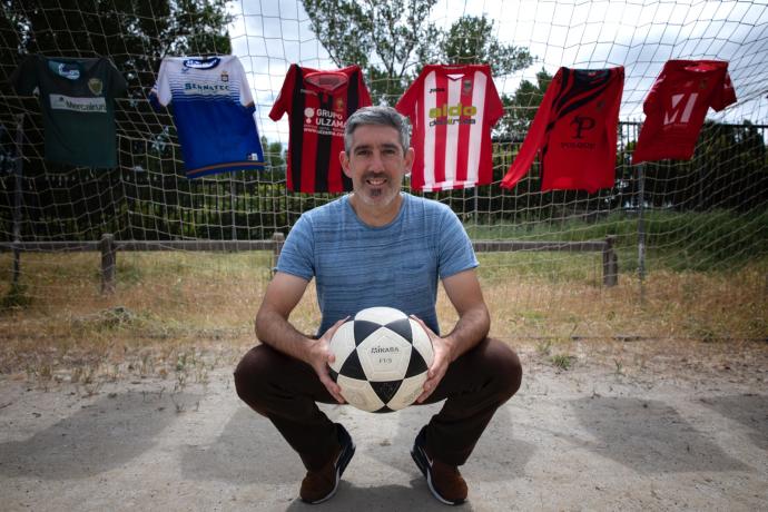 Enaut Andueza sujeta un balón delante de una portería en la que cuelgan las camisetas que ha vestido.