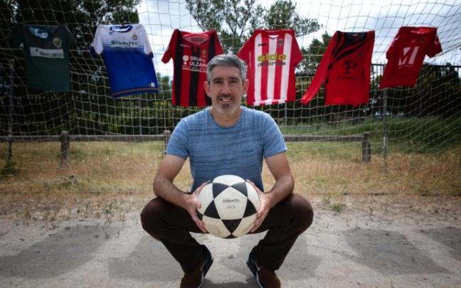 Enaut Andueza sujeta un balón delante de una portería en la que cuelgan las camisetas que ha vestido.