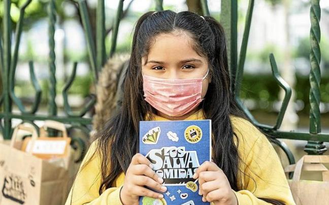 Una niña posa con el cartel anunciador del certamen.