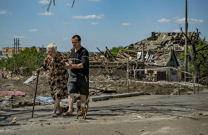 Una anciana y un hombre pasean ante los restos de una casa destruida en Donetsk.
