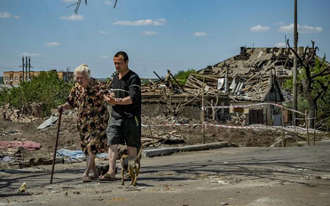 Una anciana y un hombre pasean ante los restos de una casa destruida en Donetsk.