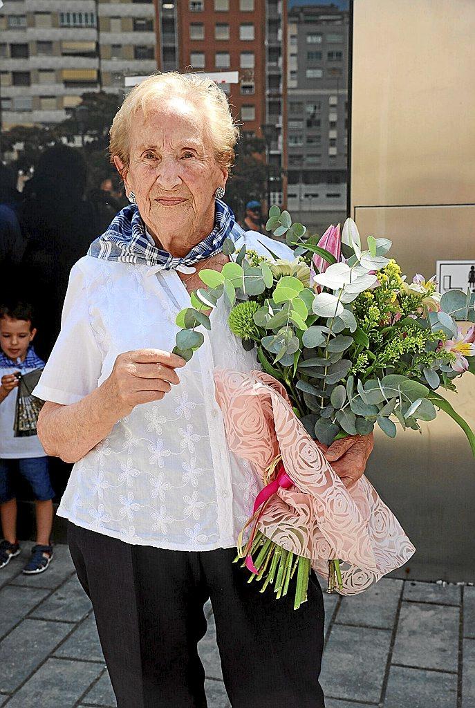 Estefanía Chocarro Mendoza, la encargada echar el chupinazo, posa junto a la ofrenda foral que le han otorgado los vecinos de Azpilagaña.