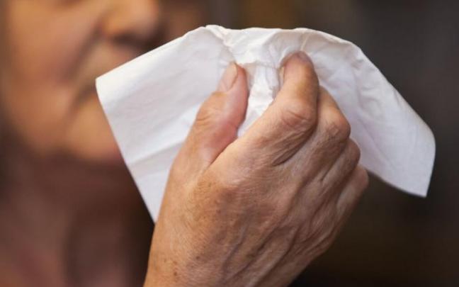 Una mujer se dispone a sonarse la nariz