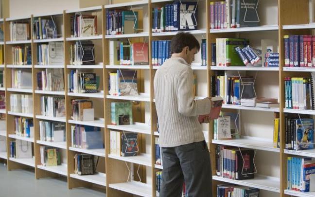 Un estudiante universitario ojeando unos libros en el interior de la biblioteca de la UPV Un estudiante universitario ojeando unos libros en el interior de la biblioteca de la UPV
