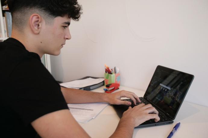 Un joven trabaja con su ordenador desde casa.