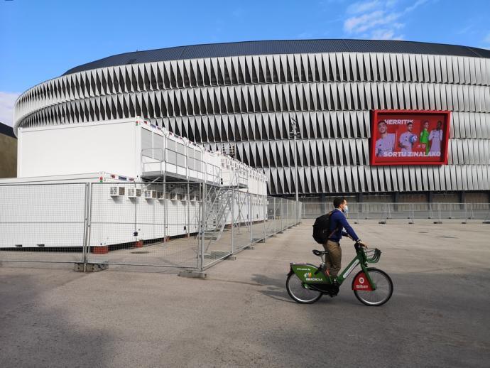 Un ciclista pasa por delante de los preparativos de la Eurocopa en la explanada de San Mamés.