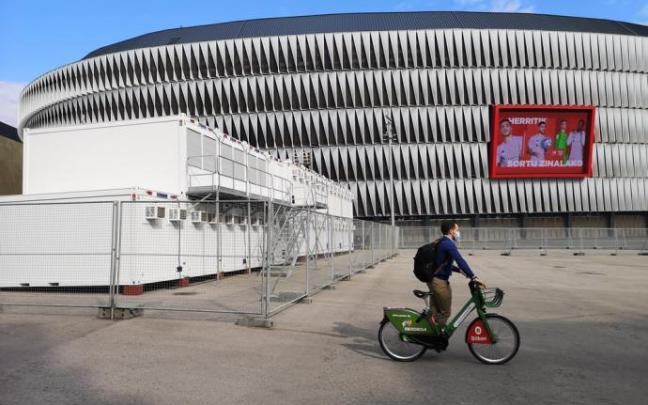 Un ciclista pasa por delante de los preparativos de la Eurocopa en la explanada de San Mamés.